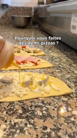 Pizza artisanale en préparation avec garniture et huile versée sur pâte posée sur plan de travail en granite.