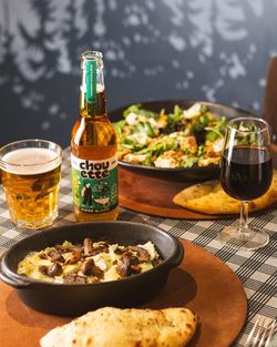 Plat crémeux aux champignons, salade fraîche, bière blonde et verre de vin rouge sur table à carreaux