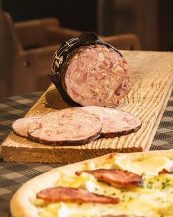 Charcuterie artisanale tranchée et pizza avec garniture de viande sur table en bois rustique