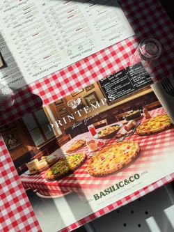 Set de table avec plusieurs pizzas artisanales sur une table à carreaux rouges, menu visible au-dessus.