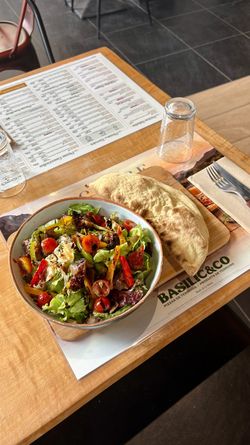 Salade fraîche avec légumes variés accompagnée d'une pizza artisanale sur table en bois au restaurant Basilic & Co