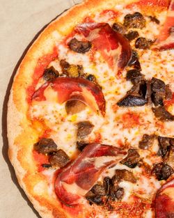 Pizza artisanale avec garniture de champignons et tranches de viande sur pâte fine et croustillante