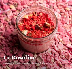 Mousse à la praline rose avec éclats de pralines roses dans un pot en verre sur un fond de pralines roses