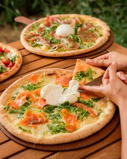 Pizza artisanale avec saumon fumé, roquette et mozzarella fondante servie sur une table en bois à Basilic & Co.