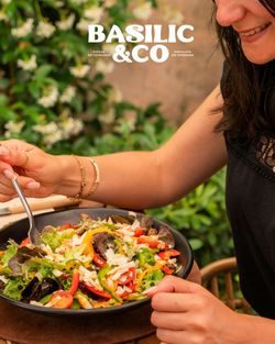 Salade fraîche avec poivrons rouges, laitues et morceaux de fromage servie dans un bol noir avec une femme prête à manger.