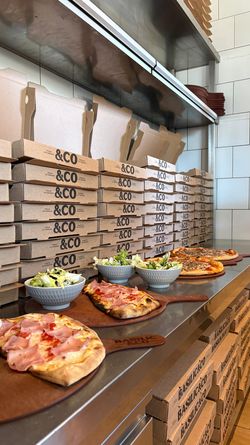 Pizzas artisanales et salades servies avec des boîtes à pizza empilées prêtes pour la livraison à Basilic & Co Voiron