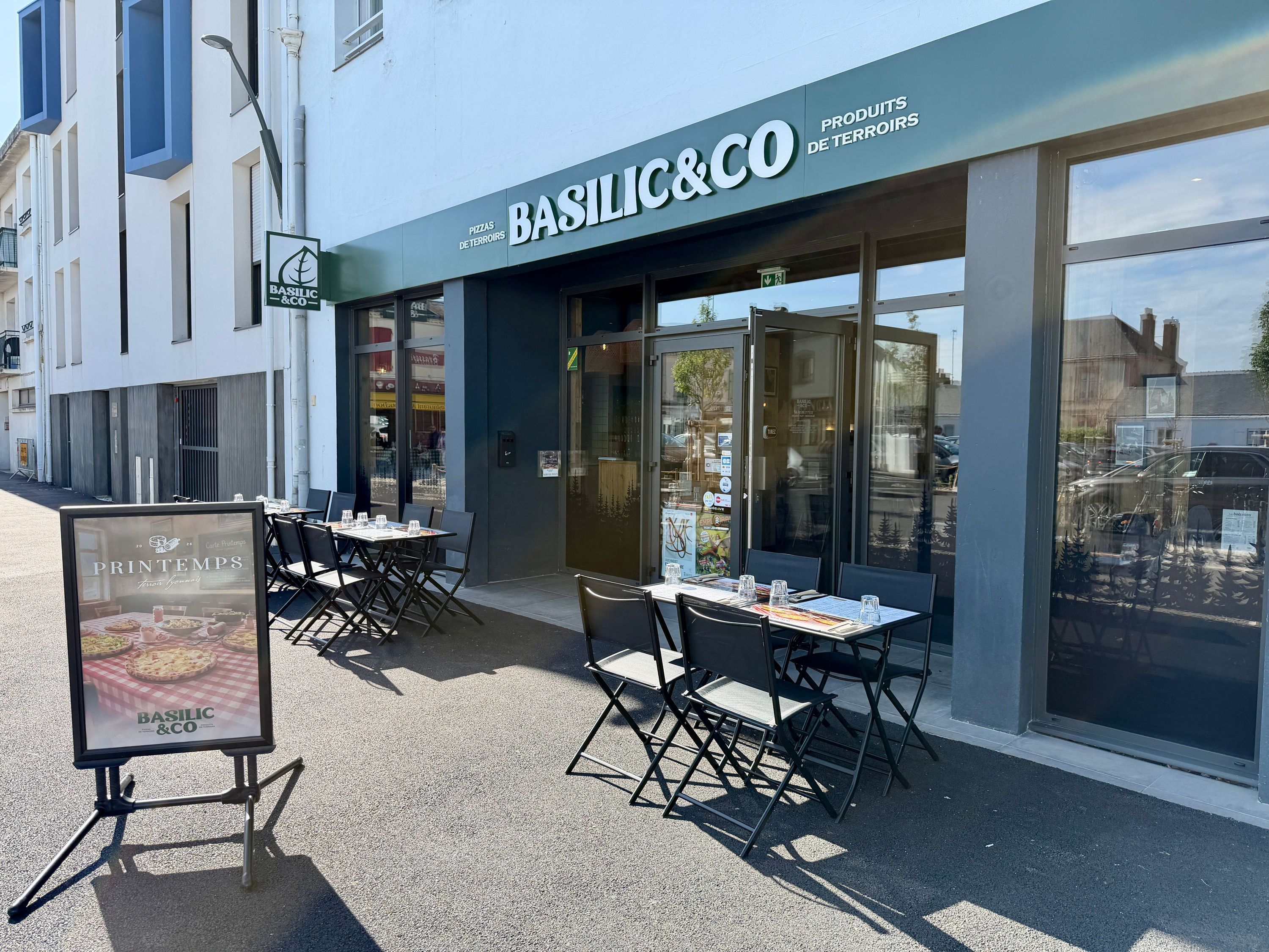 Façade du restaurant Basilic & Co à Challans avec des tables et chaises en terrasse pour pizzas à emporter.