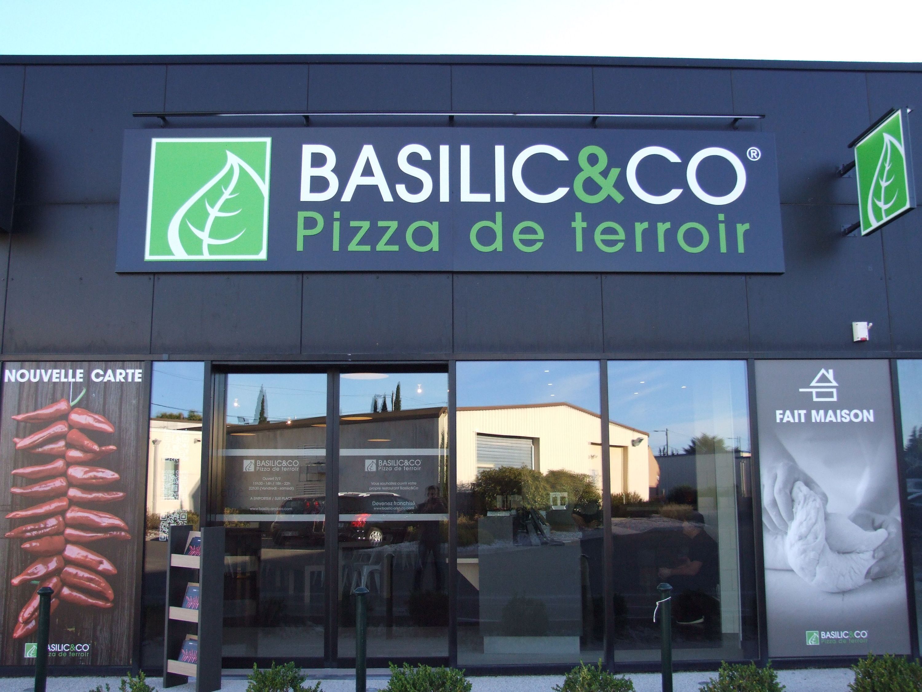 Les devantures du restaurant Basilic & Co présentent leur menu avec une accentuation sur la pizza artisanale.
