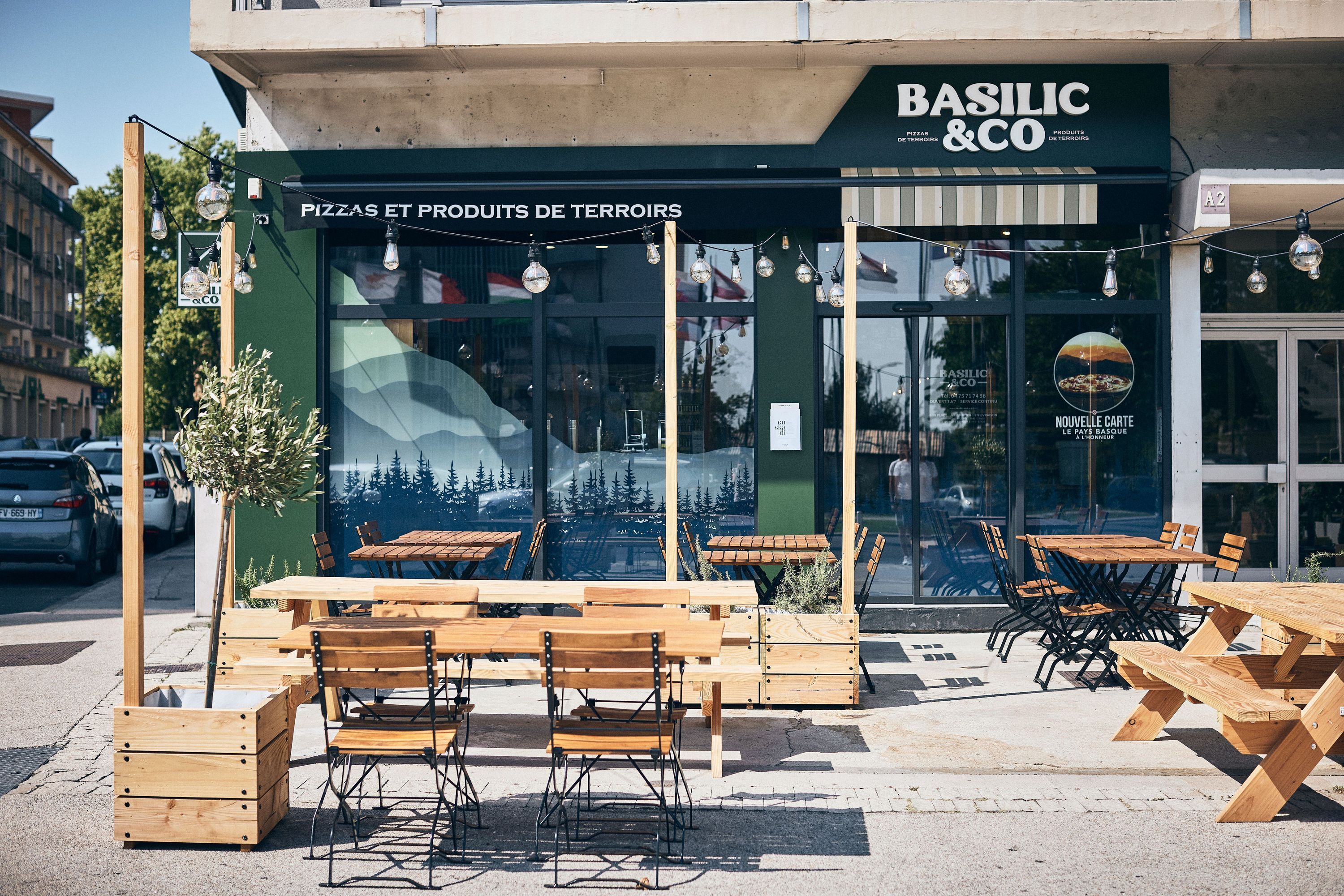Restaurant Basilic & Co avec des tables en bois à l'extérieur et une décoration moderne.