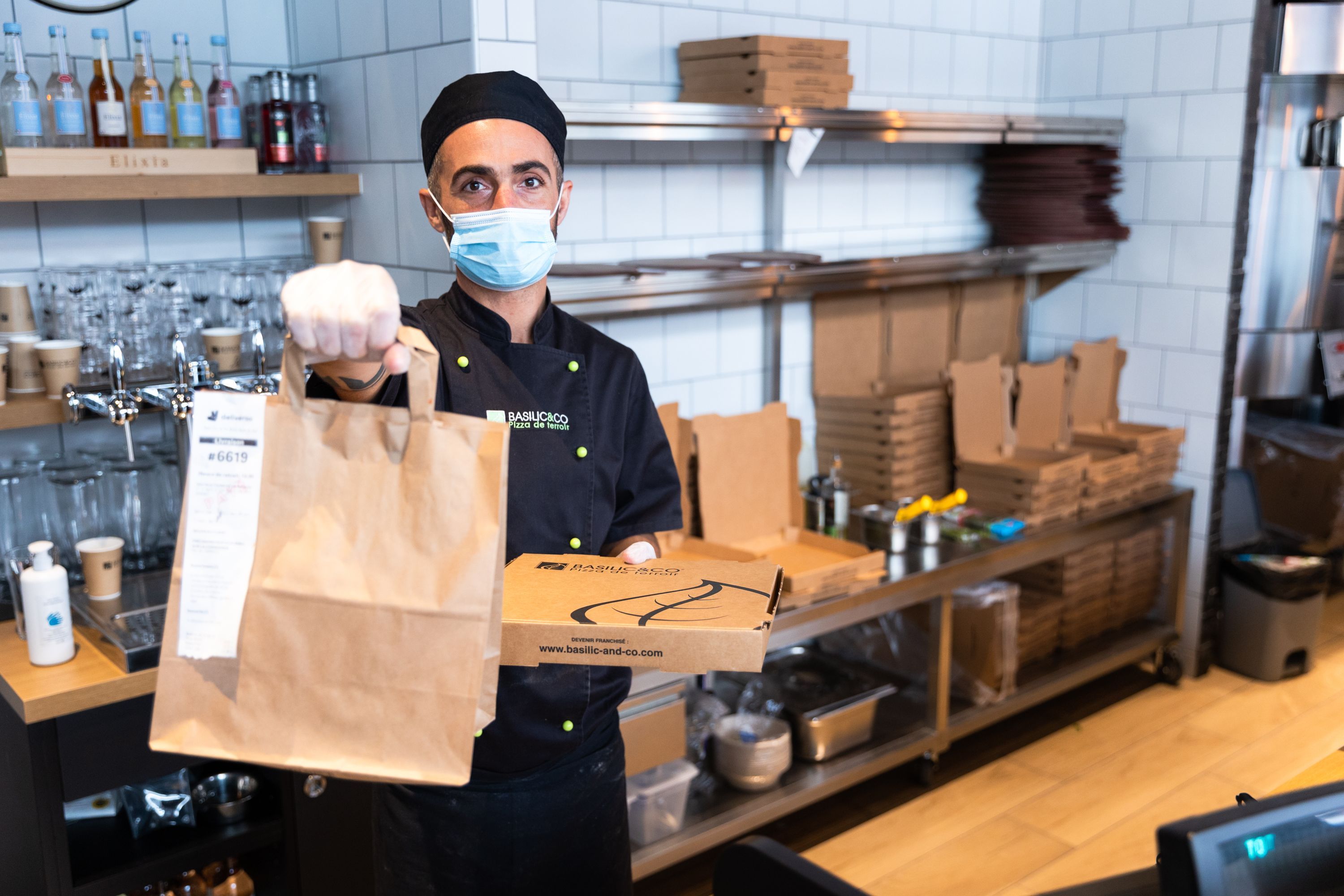 Préparation de commandes de pizzas artisanales à emporter et de salades au restaurant Basilic & Co à Nice.
