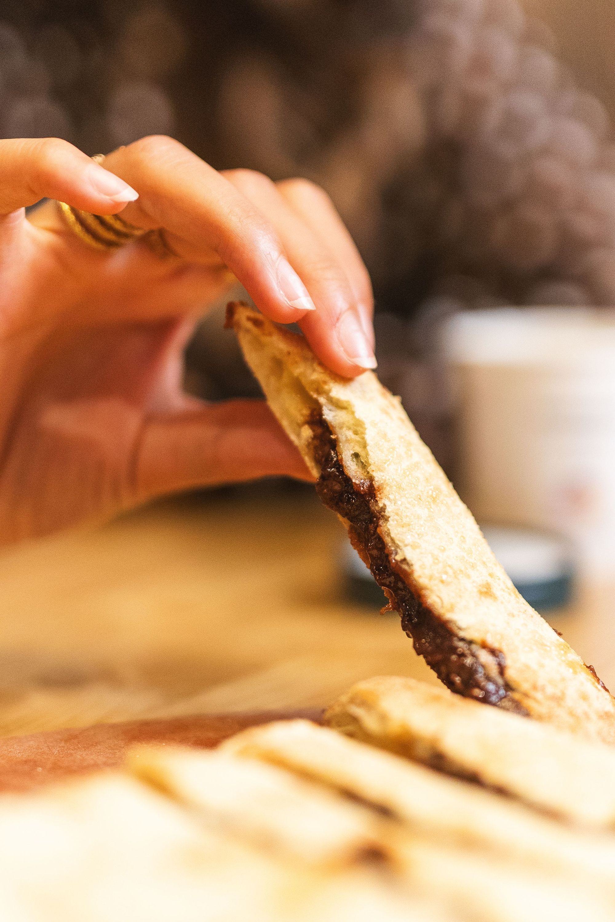 Tranche de pizza artisanale tenue à la main avec une croûte dorée et une garniture cuite visible