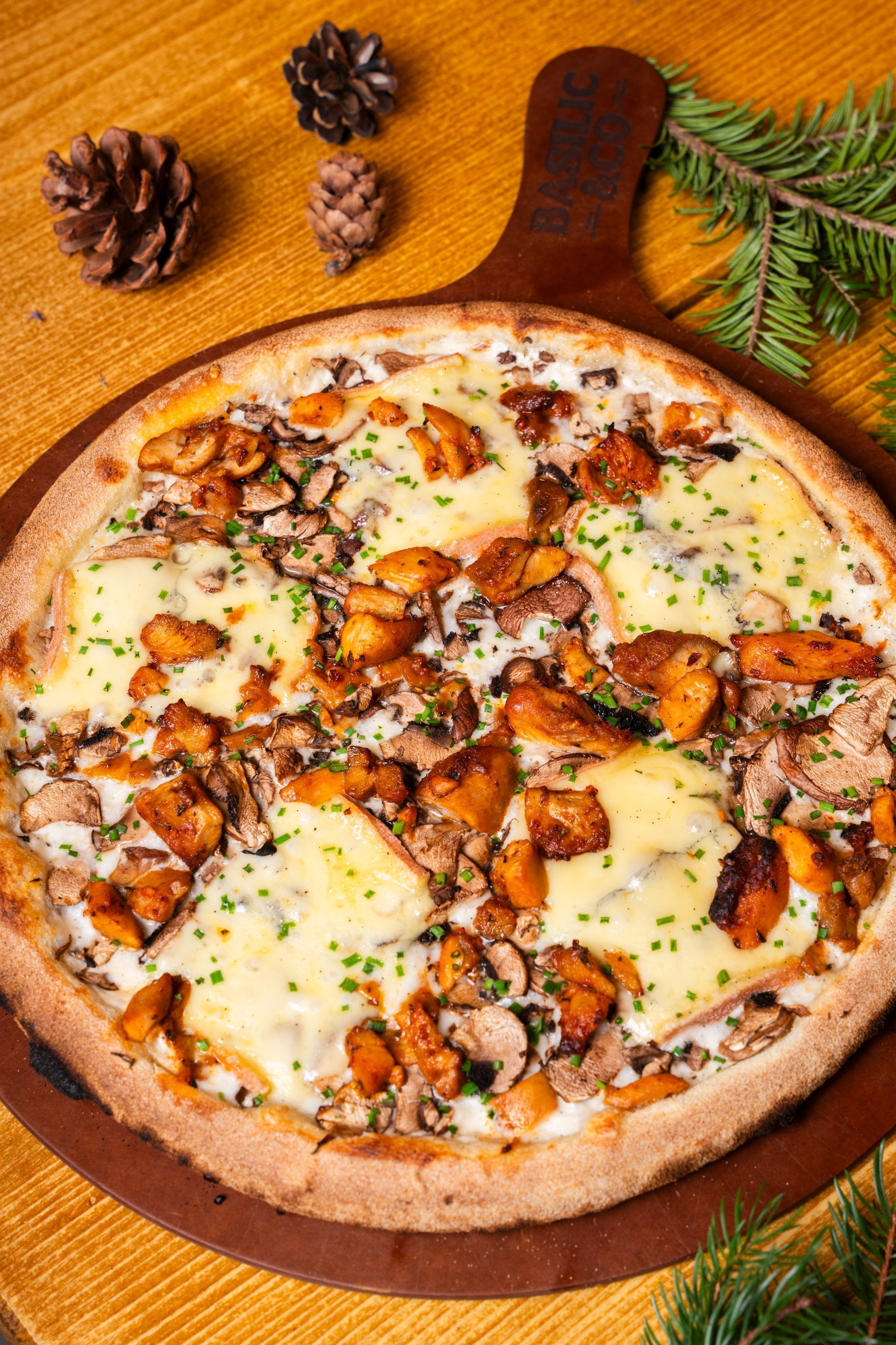 Pizza artisanale garnie de champignons et de fromage, servie sur une plaque en bois.