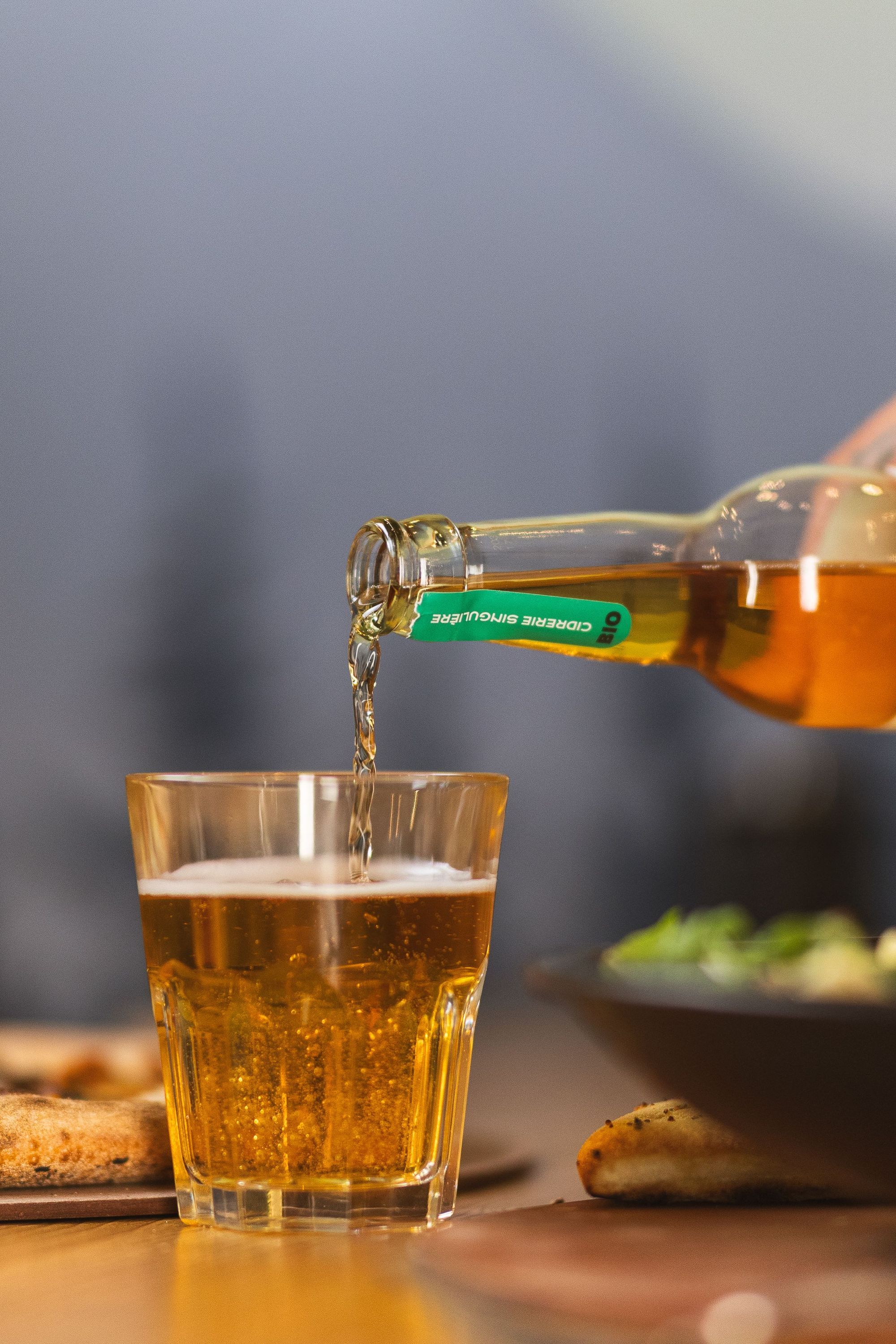 Versement d'une bière dans un verre clair avec pizza et salade en arrière-plan chez Basilic & Co à Meaux
